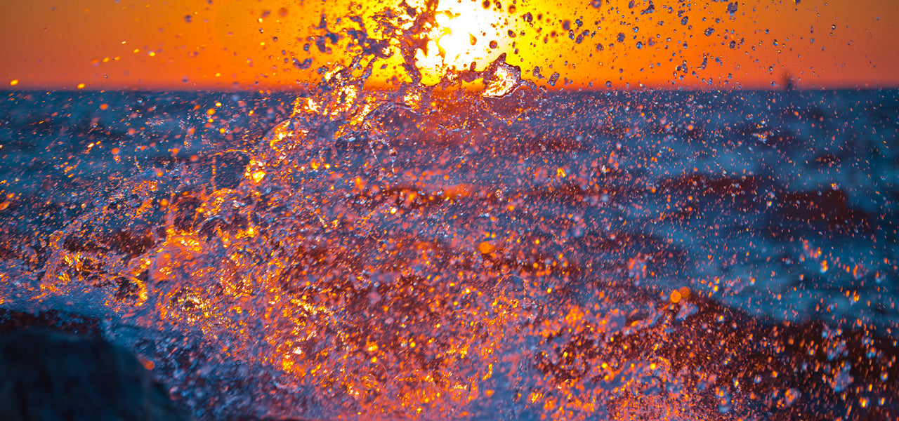 Orange sunset and blue splashes off the break wall at the entrance of a channel connecting Lake Michigan with Lake Macatawa